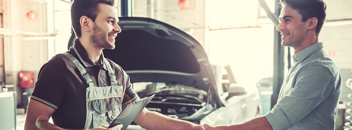 Happy customers meeting with mechanic after having his car serviced.